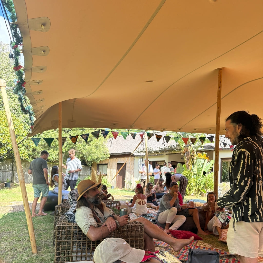 Guests relaxing on cushions under a canvas tent decorated with colourful bunting