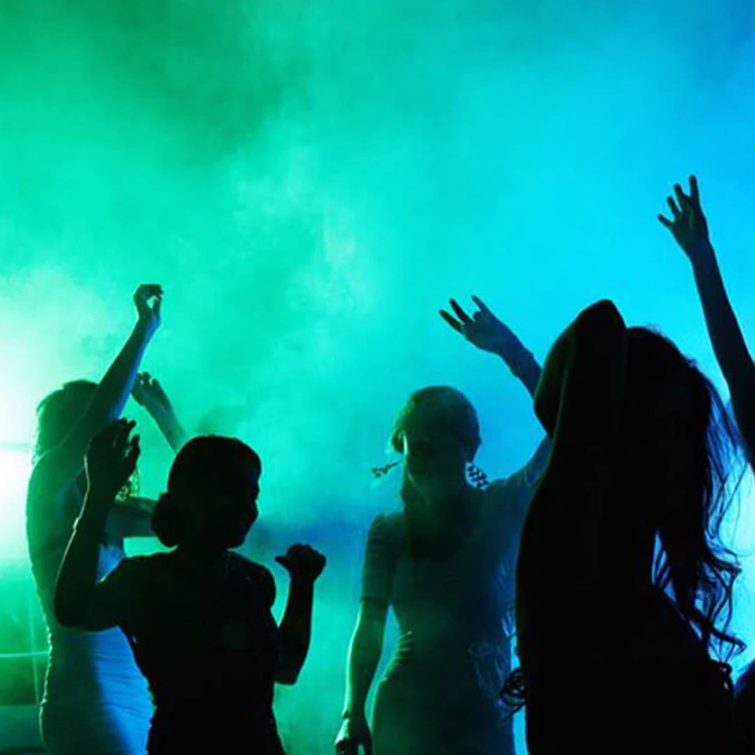Dancers silhouetted against green and blue lighting with smoke effects